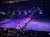 Riders on horseback carry the American flags in a parade as part of a show in an arena filled with an audience watching from tiered seating.