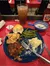 This image shows a partially eaten meal consisting of barbecue brisket, mashed potatoes, green beans, a biscuit, and gravy, accompanied by a bread roll and iced tea, with a bottle of ketchup on the side, on a table with a red cloth.