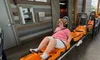 A person is seated in an orange roller coaster car at a theme park, waiting for the ride to start.