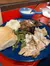 The image depicts a hearty meal consisting of mashed potatoes, green beans, pulled pork, sliced turkey breast, a dinner roll, and a small bowl of gravy or sauce, all served on a blue plate.