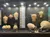 The image shows an exhibit of various ancient pottery pieces displayed behind a glass case, each with identifying labels, and a descriptive panel to the left side, possibly in a museum.