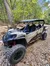 A four-seater all-terrain vehicle is parked on a rocky surface amidst a forest setting.