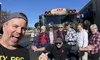 A group of cheerful people is posing for a selfie in front of a bus labeled
