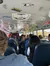 The interior of a bus is decorated with vintage license plates and colorful lights, while passengers sit on blue seats.