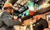 Two men are conversing in a vibrant restaurant adorned with flags, while other patrons sit at tables.