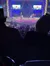 The image shows a live stage performance with two singers, a band, and an audience, featuring large digital screens displaying a sunflower.