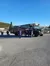 A group of people is gathered near a green tour bus parked in a lot under a clear blue sky.
