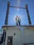 A couple is standing on the edge of a decorative building with tall smokestacks under a clear blue sky.
