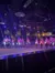 A group of performers on horseback carry American flags under dramatic stage lighting in an indoor arena setting.