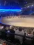 The image shows an indoor arena with an audience watching riders on horseback participating in a performance or show.