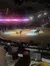 The image shows an indoor arena where a Western-themed horse performance is taking place, with an audience seated in front enjoying the show.