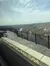 The image shows a scenic overlook with a metal railing, offering a view of a winding river and expansive landscape under a partly cloudy sky.