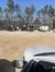 The image shows a dirt lot with several off-road vehicles parked near a small building labeled