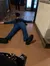 A person in a blue suit is lying on the floor with a hat nearby in what seems to be a restaurant or bar setting.