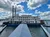 A large riverboat with two prominent smokestacks is docked at a pier under a partly cloudy sky.