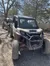 Two off-road vehicles are parked on a dirt path in a wooded area.