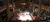 The image shows a lively, two-tiered venue decorated with holiday garlands, where a band is performing on a central stage surrounded by an engaged, seated audience.