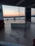 A calm, open deck overlooks a body of water and distant hills under a colorful sunset sky.