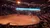 A live arena show is happening with performers on horseback wearing colorful outfits, surrounded by a cheering audience.