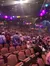 A large crowd of people are gathered in an auditorium illuminated by colorful hanging lights.