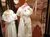 The image features a vintage-style display with mannequins dressed in white, lace-trimmed dresses, accompanied by a lace umbrella and hanging balloon-themed lights.