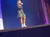 A woman in a sparkly dress is singing on stage under blue lighting.