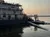 The image shows a paddle boat docked on calm water during a peaceful sunset.