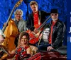 A group of five musicians poses with their instruments in front of a blue textured background