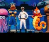 The image shows a vibrant underwater scene with a smiling cartoon shark colorful sea creatures and the text Fun for all ages along with The Columns Concert and Event Center logo