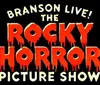 The image is a colorful theatrical poster for The Rocky Horror Picture Show featuring an ensemble cast in flamboyant costumes standing confidently on stage