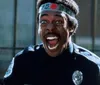 The image features a black-and-white close-up of a man passionately singing into a microphone with an inset color photo of a man in a police uniform excitedly shouting