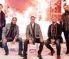 Five men in winter clothing are posing against a festive snowy backdrop