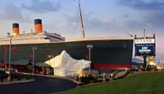 The image shows a large replica of the Titanic ship, complete with an iceberg, outside the Titanic Museum Attraction, with a sign indicating