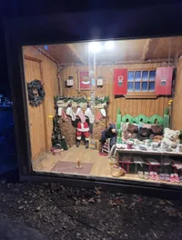 A festive diorama displaying a miniature scene with teddy bears dressed in human clothes, engaging in various activities around a cozy cabin-like room.
