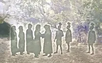 Silhouettes of people dressed in historical clothing appear to be conversing in a wooded area.