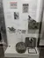 The image shows a museum display case featuring items related to war pigeons, including informational posters, a model pigeon, and pigeon-related artifacts.