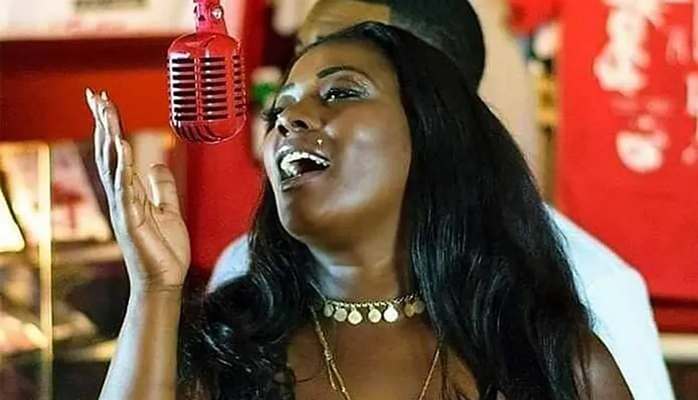 A woman is singing passionately into a red vintage microphone