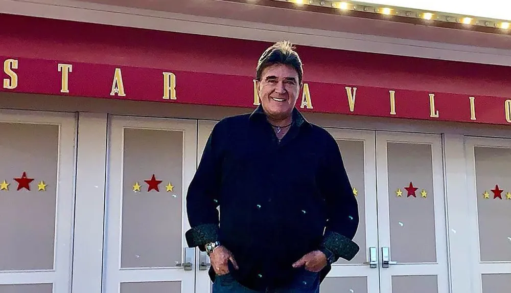 A man is standing in front of a building labeled Star Pavilion smiling at the camera