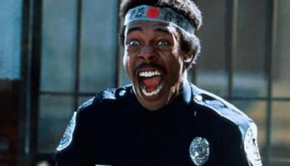 A person dressed as a police officer has a surprised and enthusiastic expression while wearing a headband