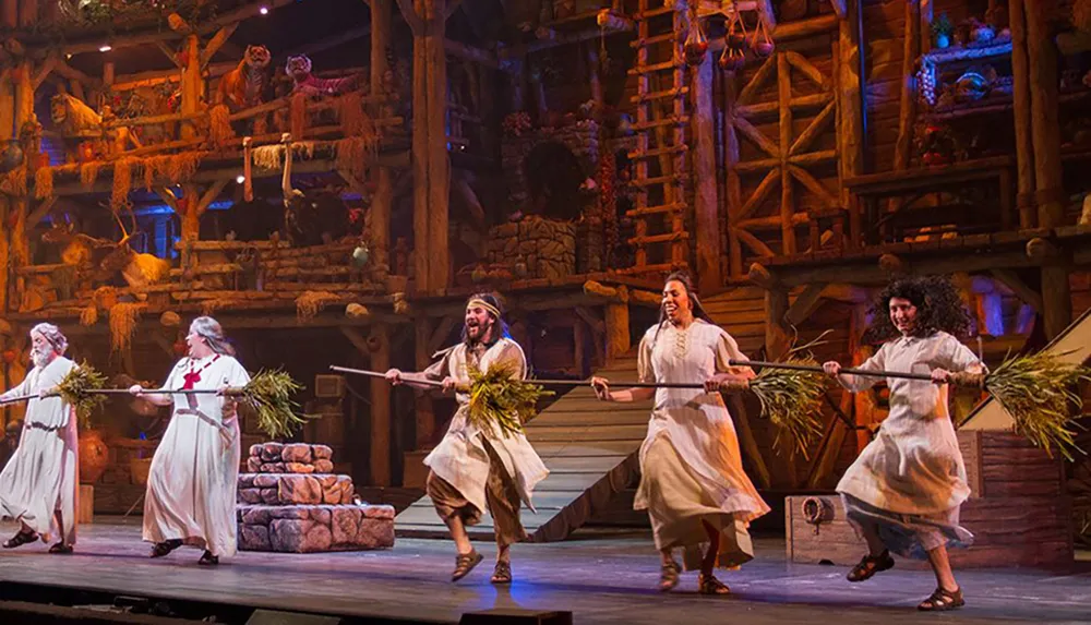 Actors in historical costumes perform a lively dance on a rustic wooden stage evoking a scene from a bygone era