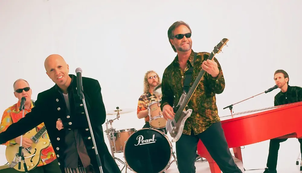 A band of five musicians is performing featuring a singer guitarist bassist drummer and pianist