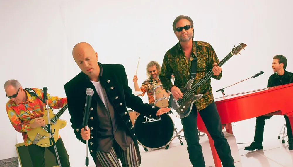 A band is energetically performing with a singer guitarist bassist drummer and keyboardist on a white background